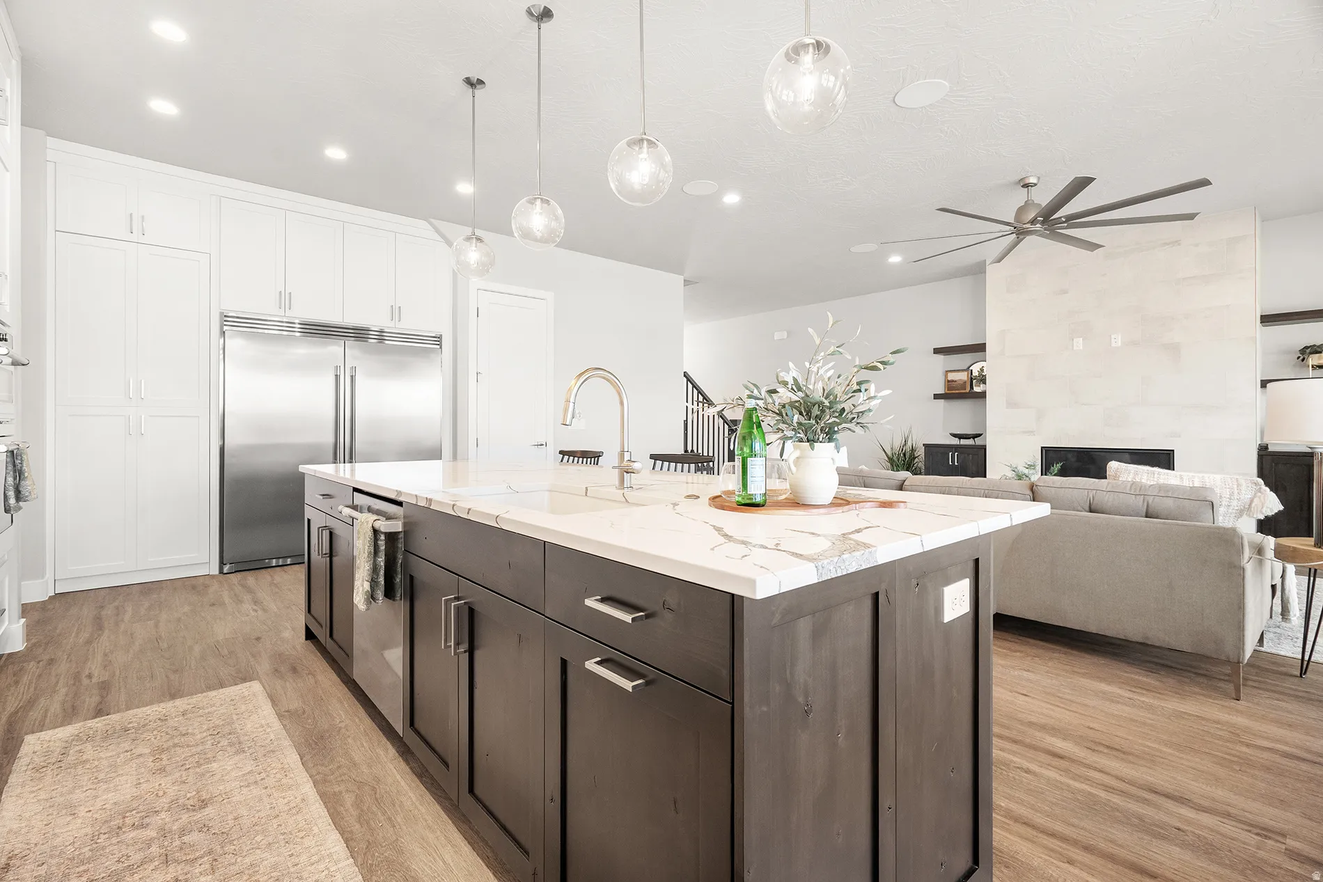 Spacious kitchen island with a waterfall countertop, integrated sink, and modern pendant lighting