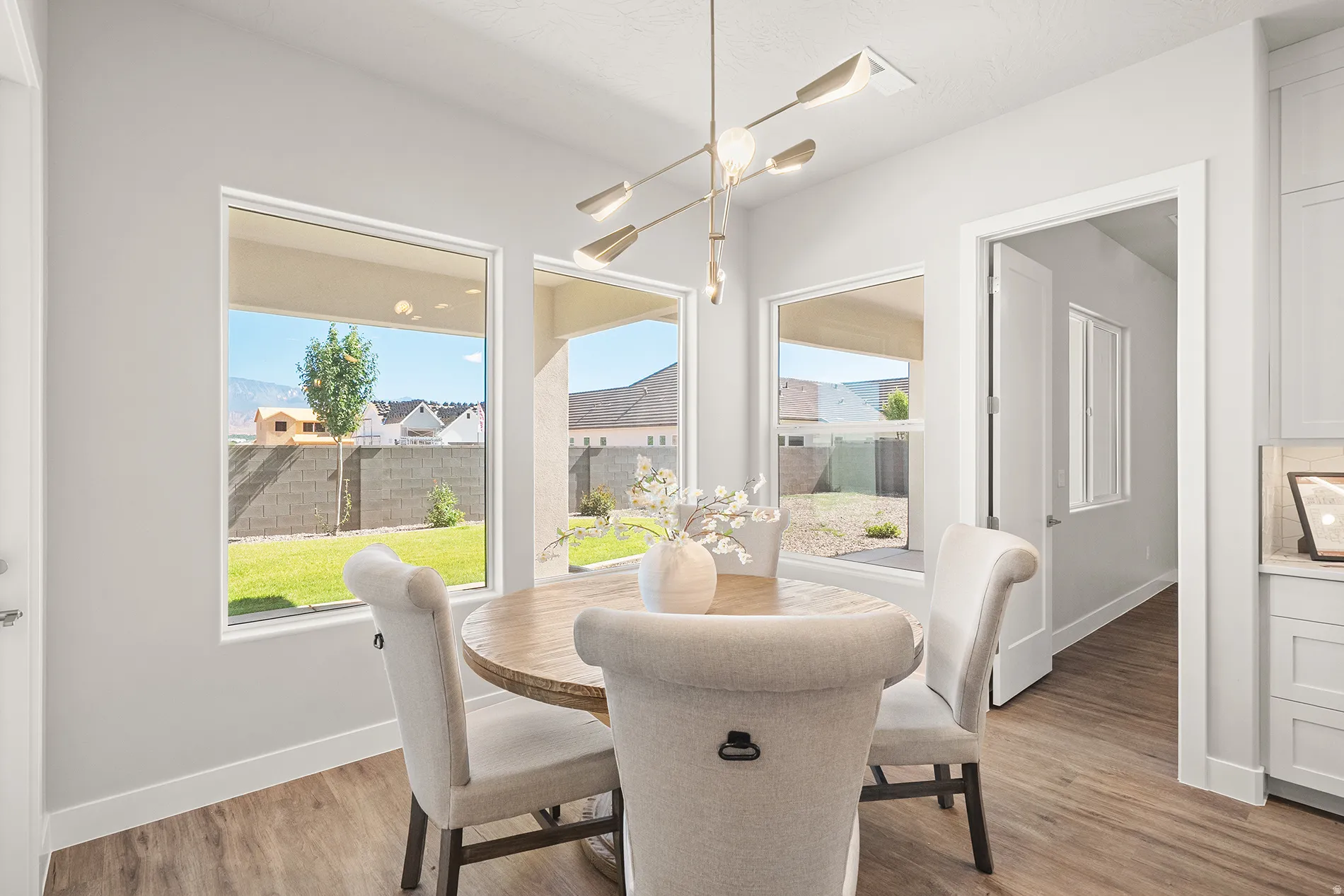 Dining area featuring wood-finish flooring, a modern linear chandelier, and multiple rectangular windows