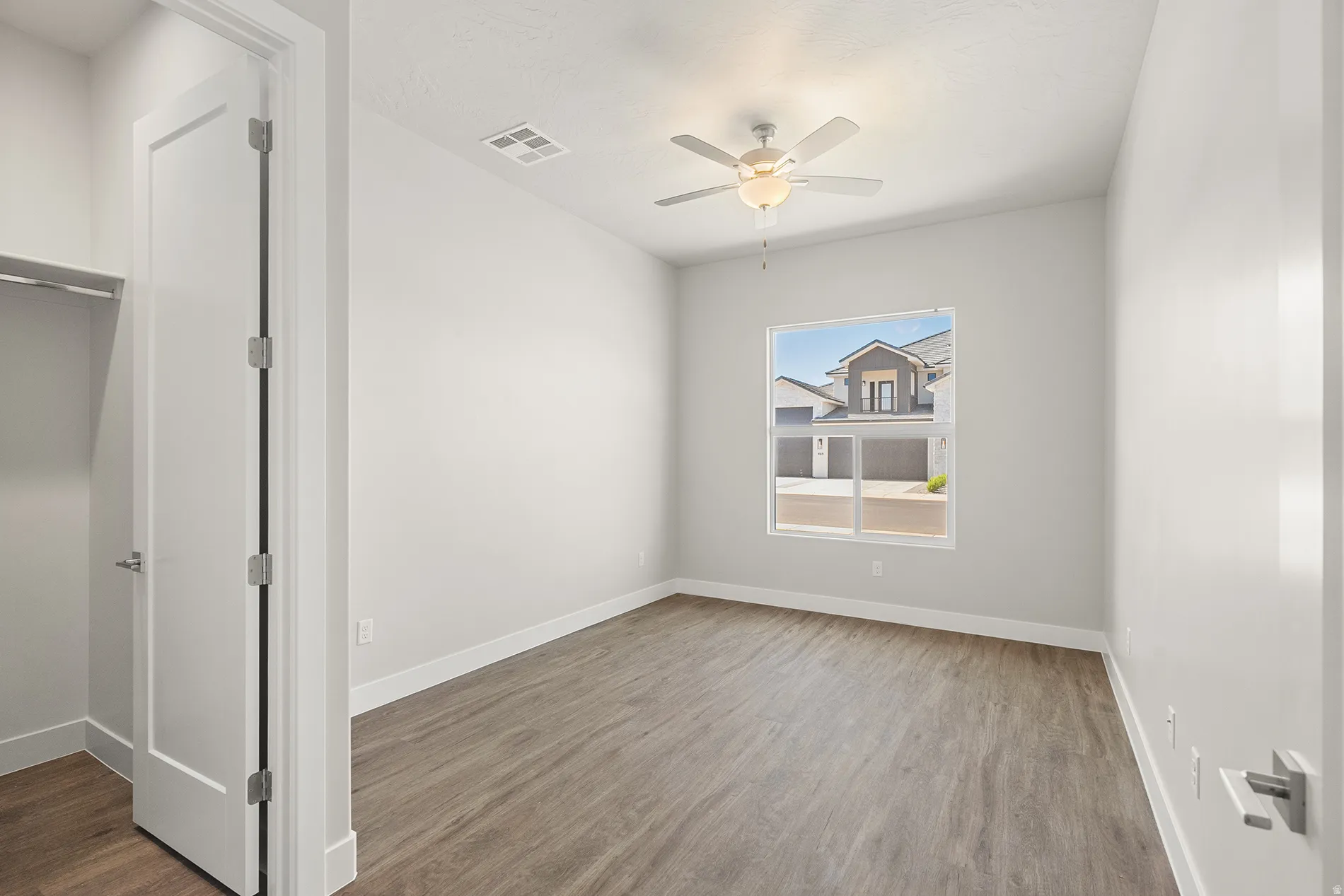Room featuring wood-finish flooring, white baseboards, and light gray walls