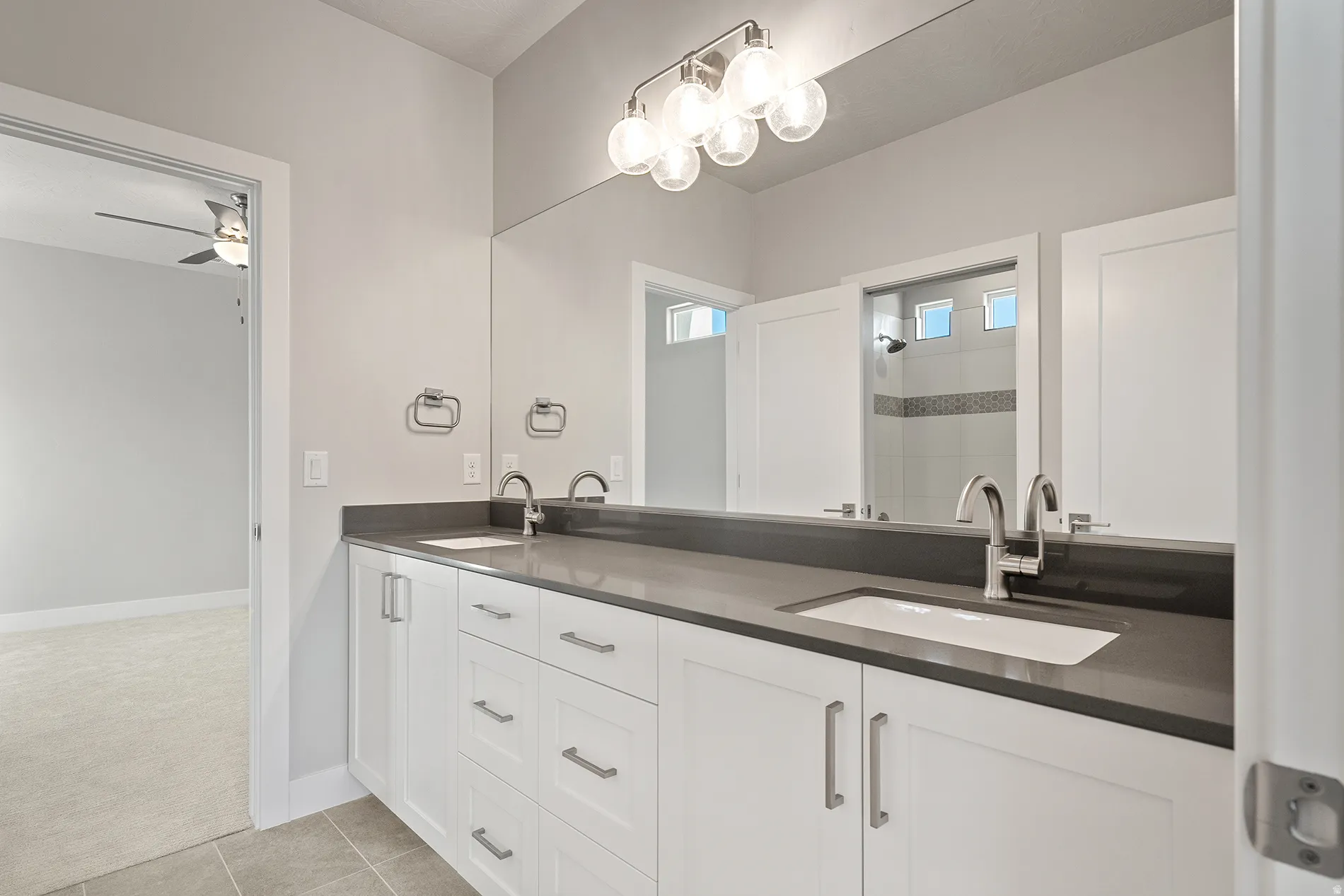 Dual sink vanity featuring a dark countertop and white cabinetry
