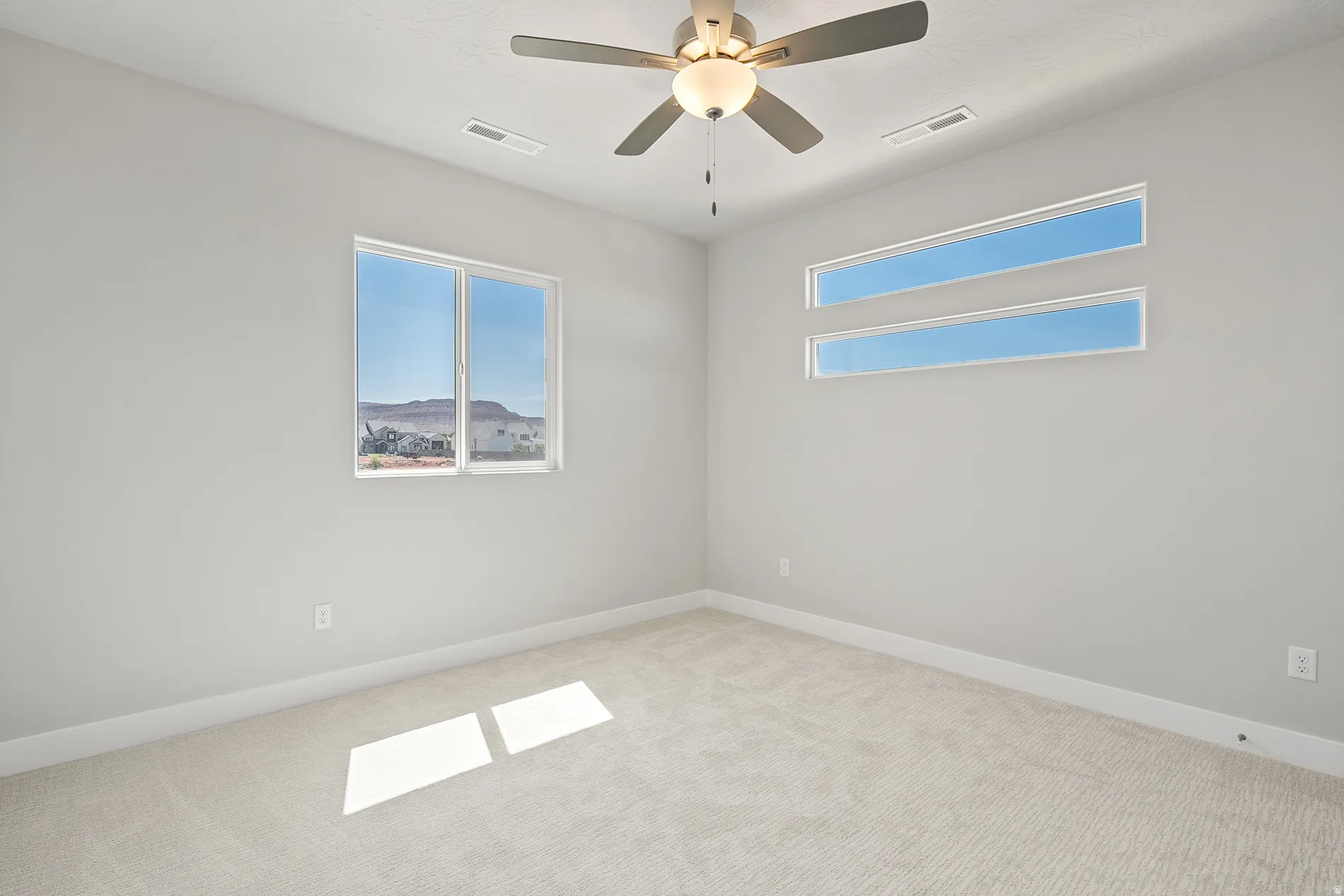 Light-filled room featuring carpet flooring, a ceiling fan with integrated lighting, a large picture window, and two horizontal transom windows