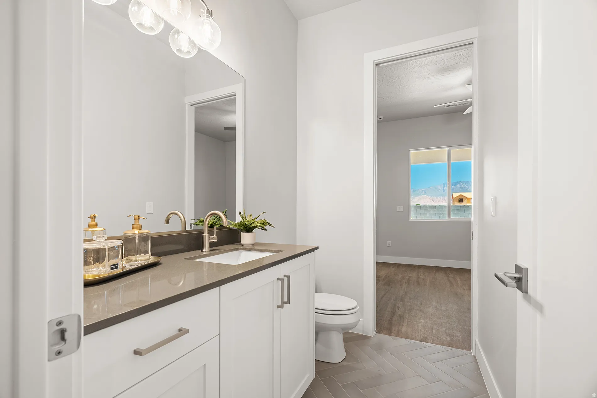 Bathroom featuring a white vanity with a dark countertop, an undermount sink, and a mirrored wall