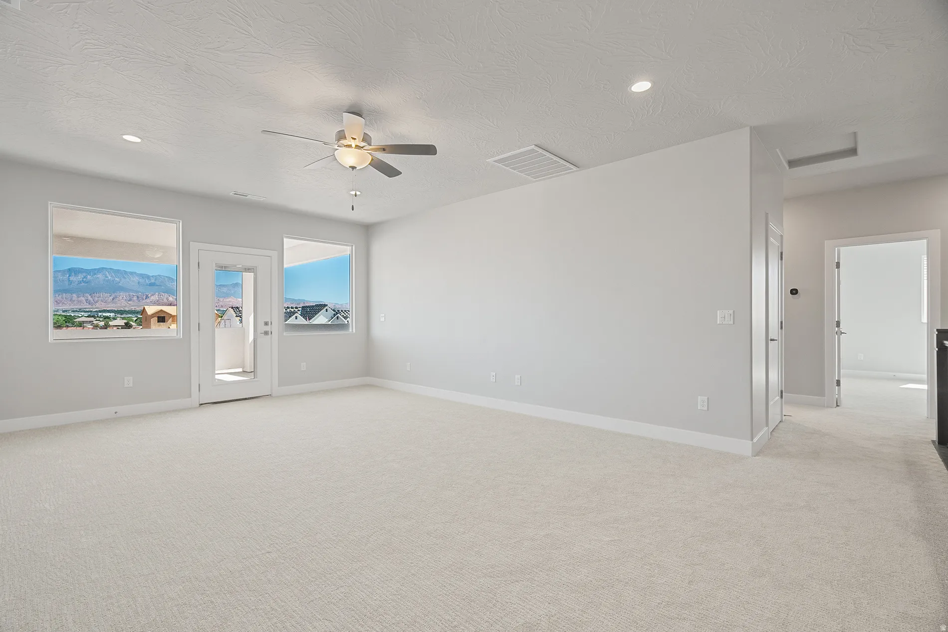 Upstairs Spacious carpeted room featuring a ceiling fan, recessed lighting, and a glass-paneled door opening to an outdoor area