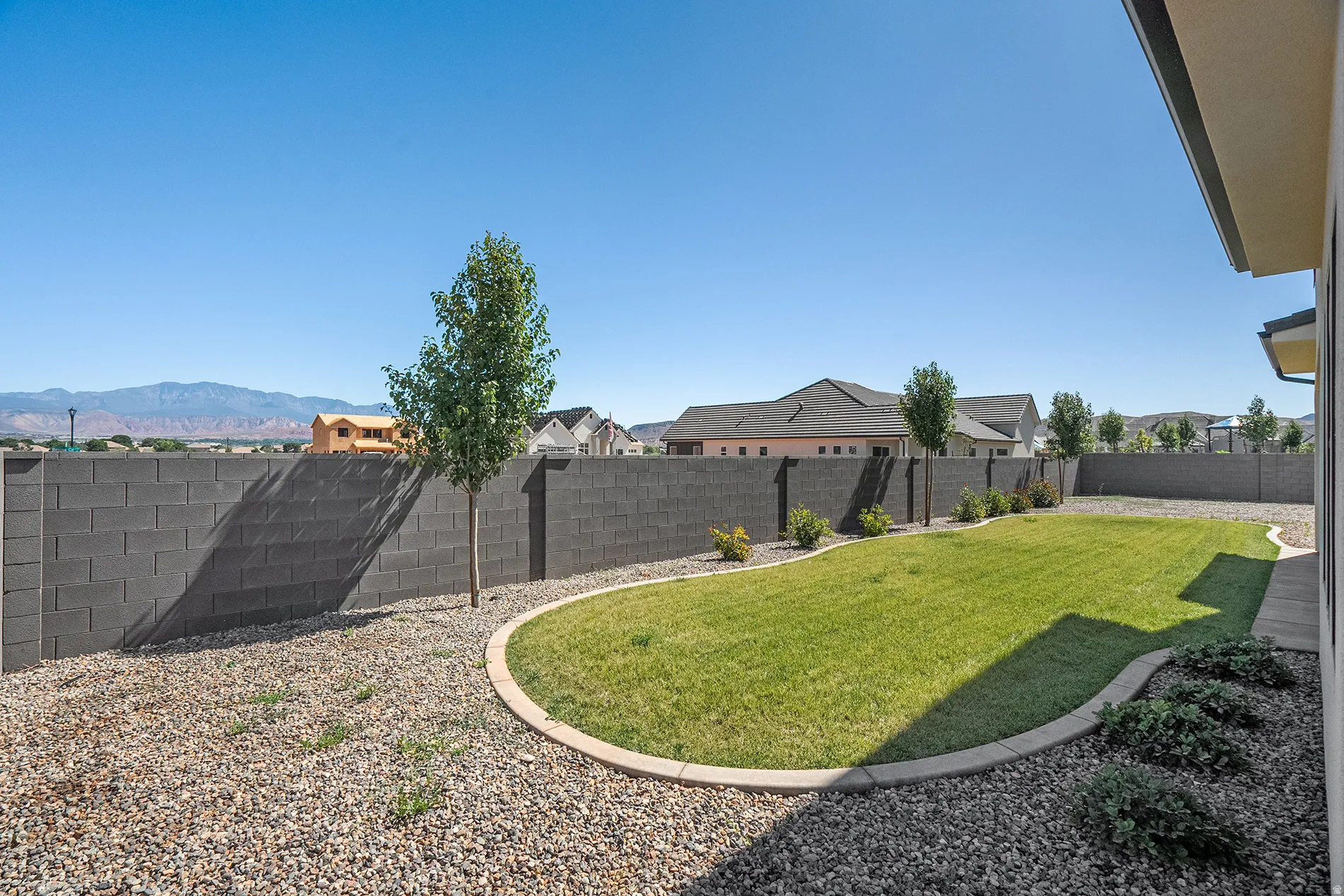 Expansive backyard featuring a manicured lawn, established landscaping, and a substantial block wall perimeter