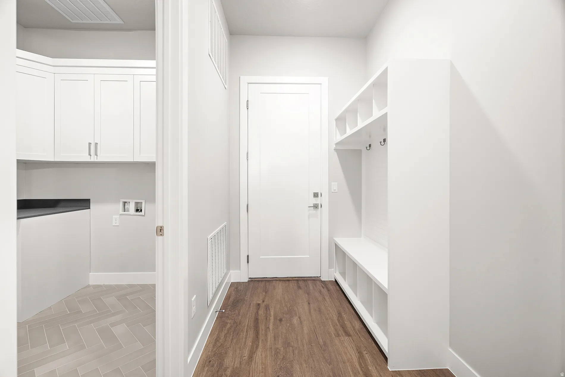 Entryway with wood-finish flooring and a built-in mudroom bench featuring cubbies and coat hooks