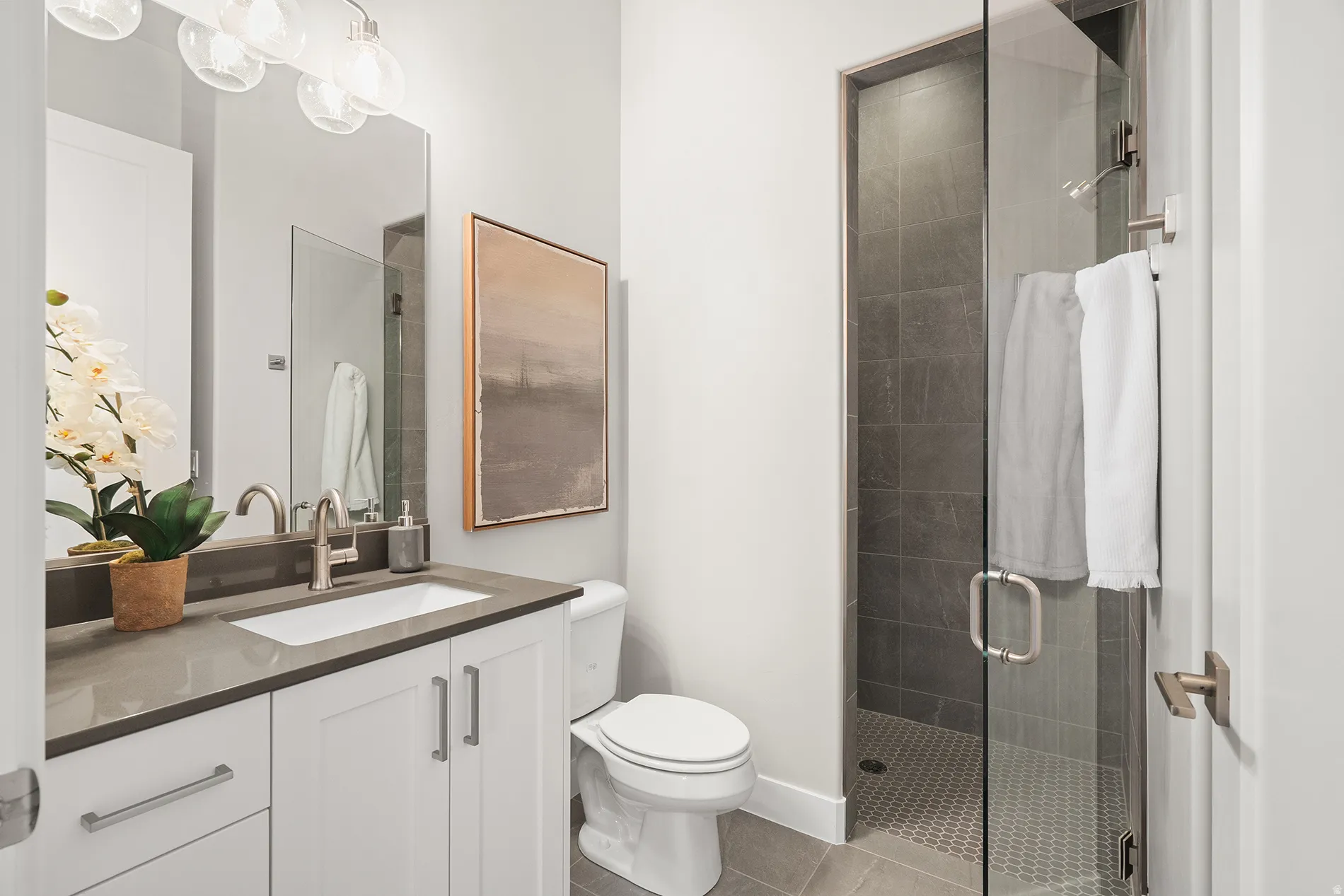 Bathroom featuring a glass-enclosed shower with dark tiled walls and a hexagonal tiled floor