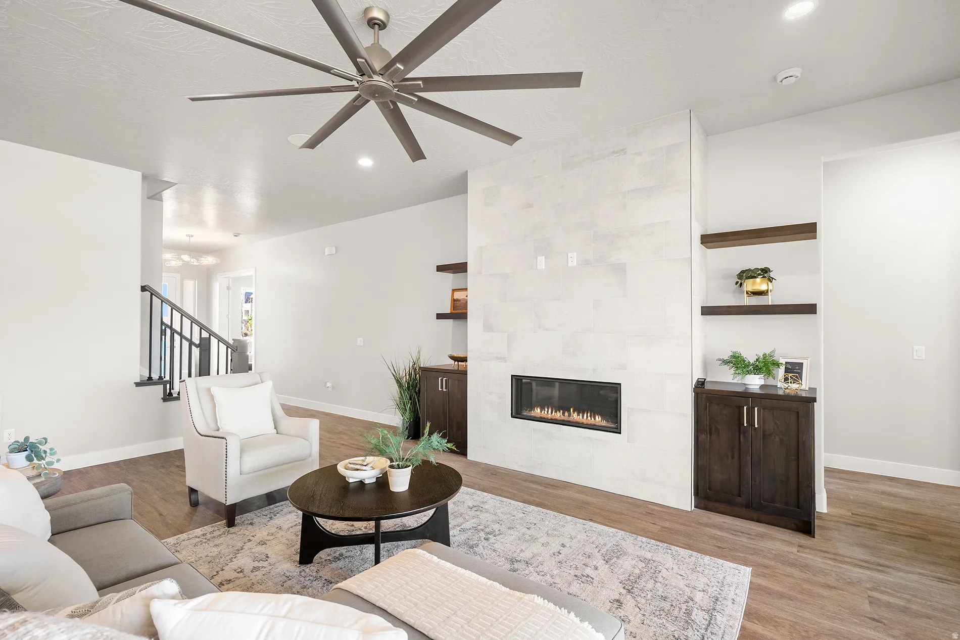 Spacious living area featuring wood-finish flooring, a contemporary fireplace with a stone surround, and recessed lighting