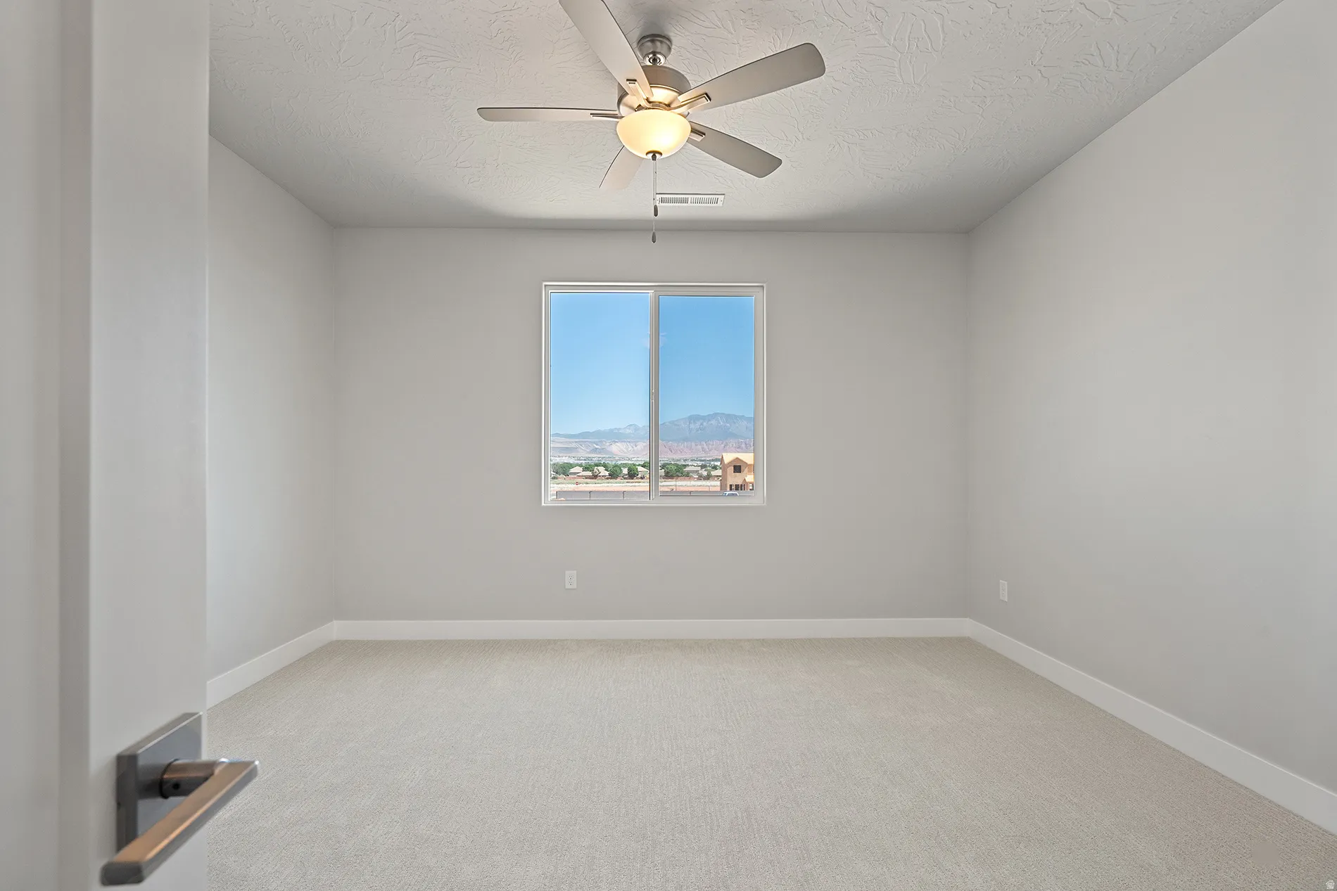 Expansive room featuring light gray walls, plush carpeting, a modern ceiling fan, a large window, and white trim
