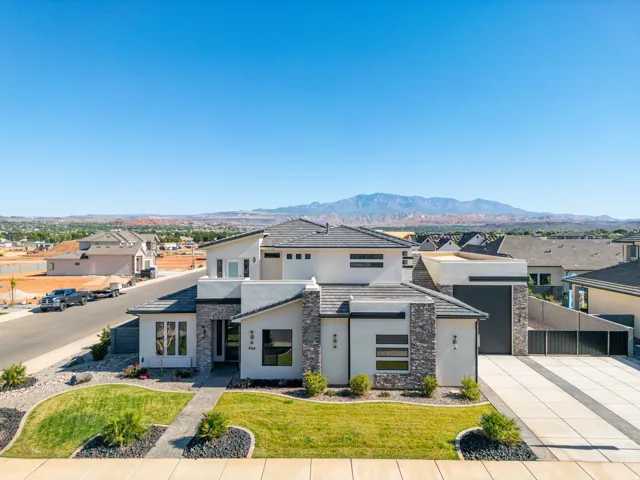 Modern architectural facade with stone accents, stucco finish, and a dark tile roof