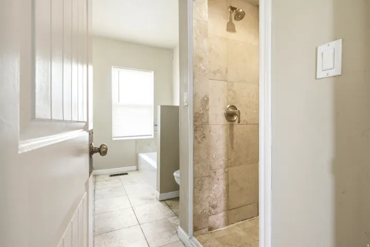 Tiled shower with a bronze-finish showerhead and controls