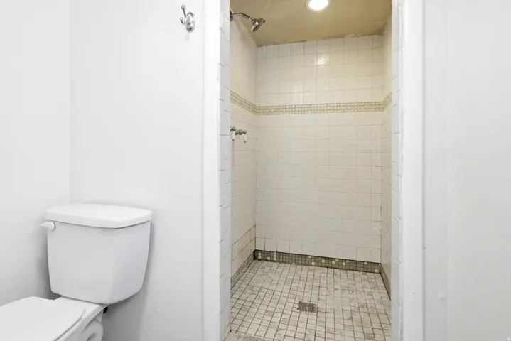 White tile shower with decorative accent band and integrated lighting