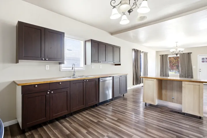 Kitchen featuring dark wood cabinetry, light wood-finish countertops, stainless steel sink, and wood-finish flooring