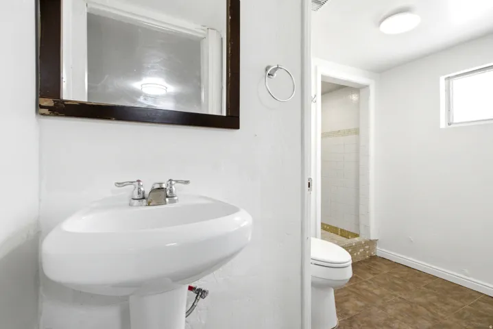 Pedestal sink with chrome fixtures and a wall-mounted mirror