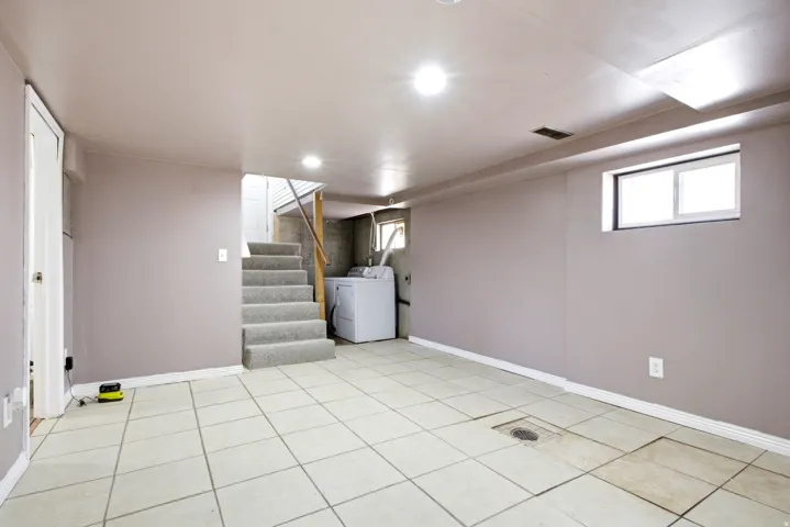 Versatile basement space featuring light-toned tile flooring, recessed lighting, and painted walls