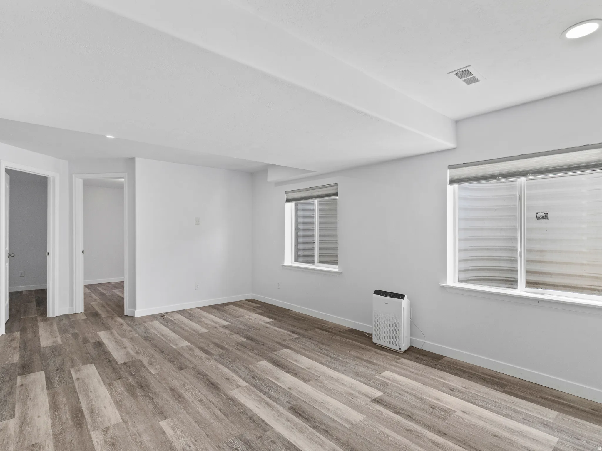 Spacious room featuring wood-finish flooring, white baseboards, and bright white walls