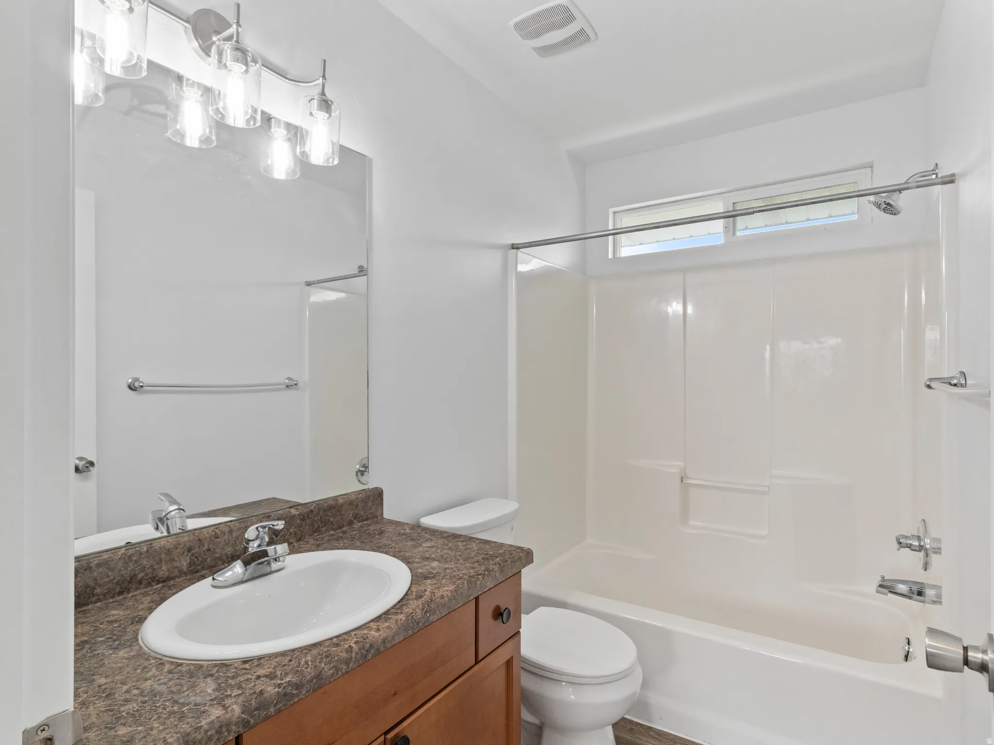 Bathroom featuring a single vanity with wood-finish cabinetry, a brown speckled countertop, and an oval undermount sink