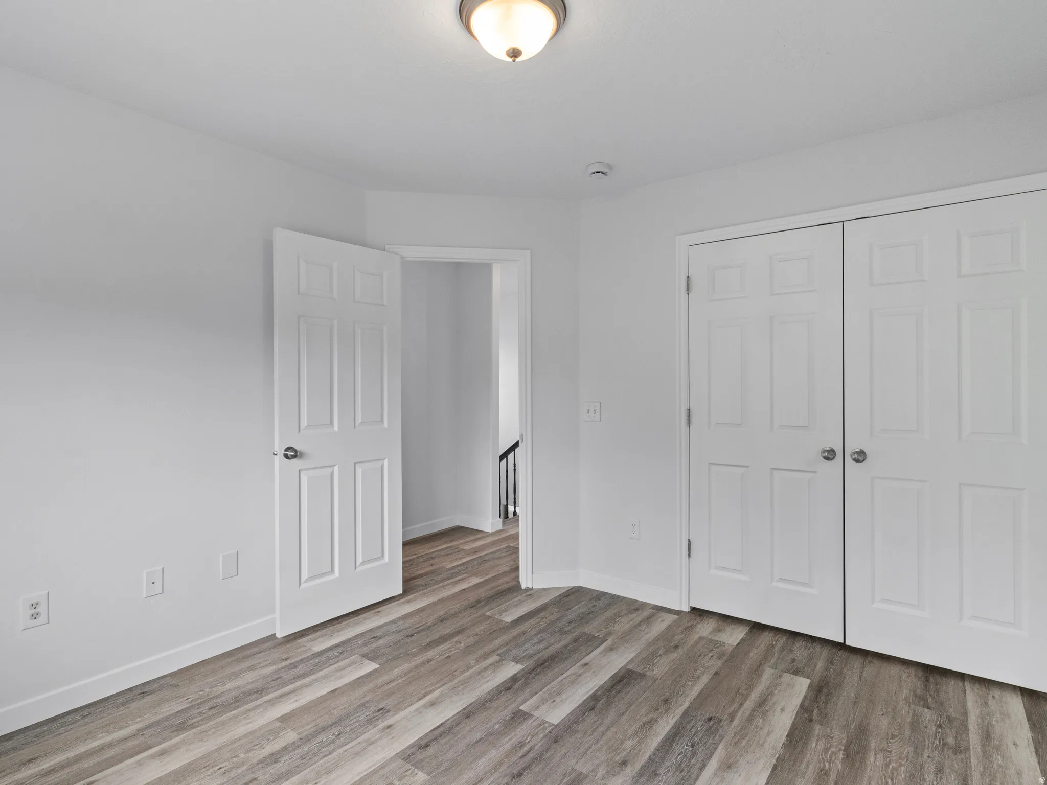 Interior space featuring wood-finish flooring, white walls, and a ceiling-mounted light fixture