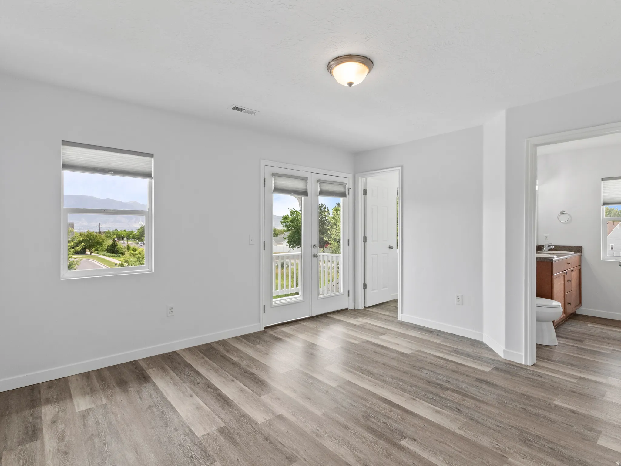 Bright interior room featuring wood-finish flooring, white walls, and a ceiling-mounted light fixture