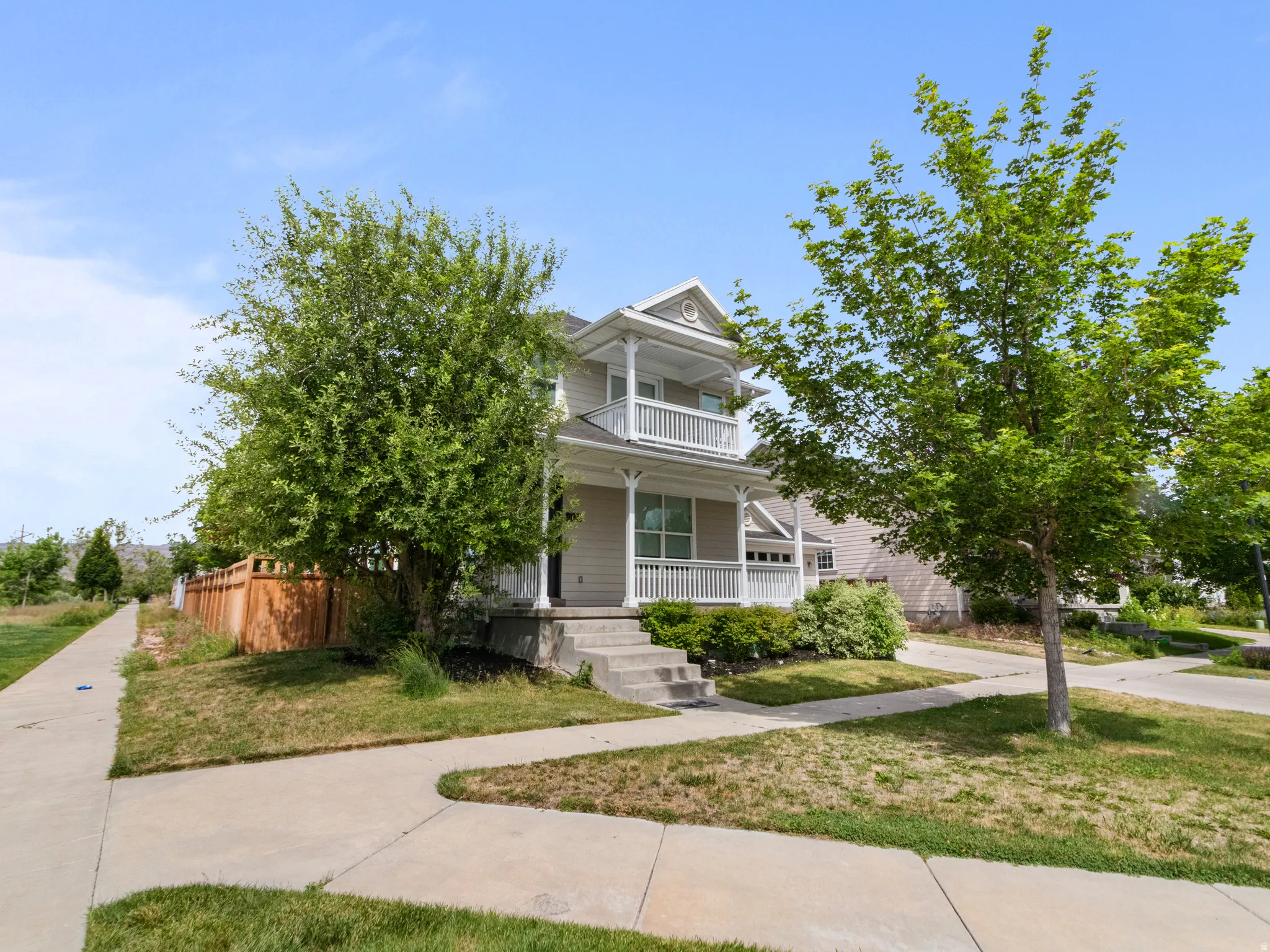 Two-story residence featuring a covered front porch, upper-level balcony, and attached garage