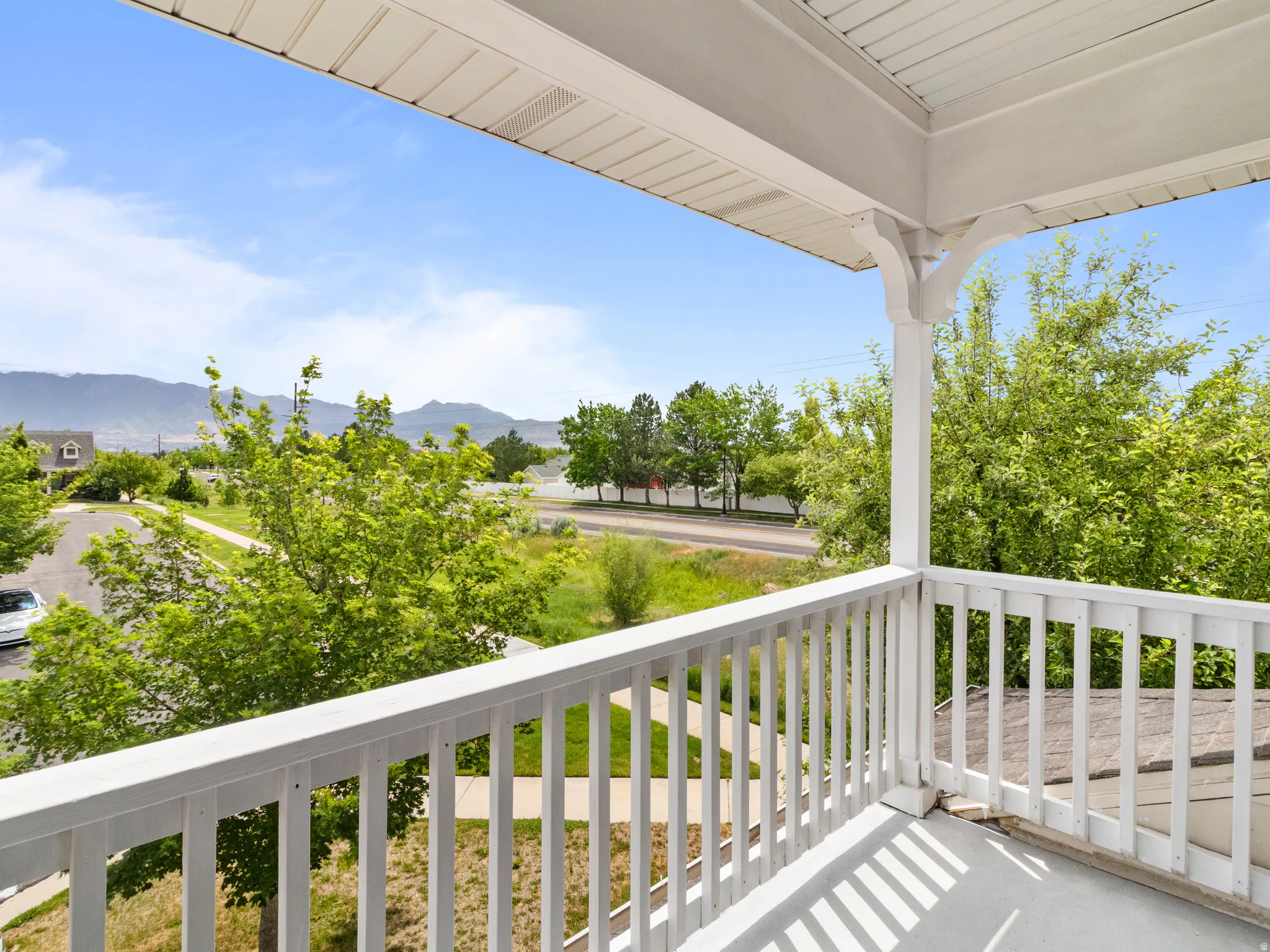 Outdoor balcony featuring a white railing, support columns with decorative brackets, and a painted floor