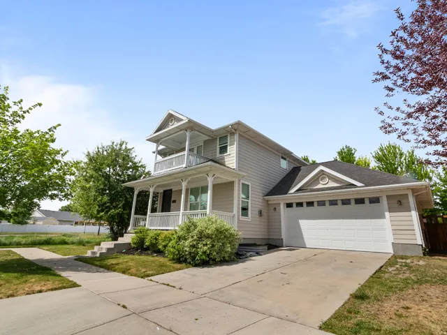 Two-story residence featuring a covered front porch with white railings, a second-story balcony, and horizontal siding
