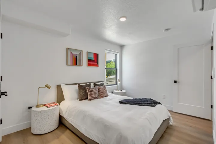 Bedroom featuring wood-finish flooring, a window offering natural illumination, and a modern ceiling light fixture