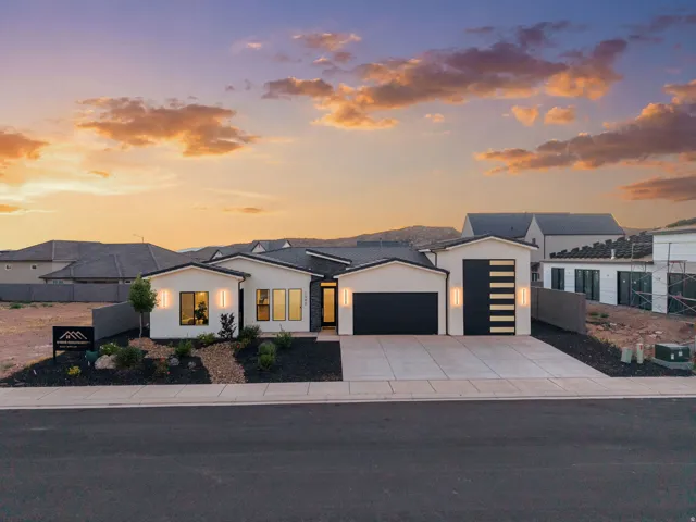 Modern single-story residence with a light-colored stucco exterior, black accents, and a low-pitched roofline