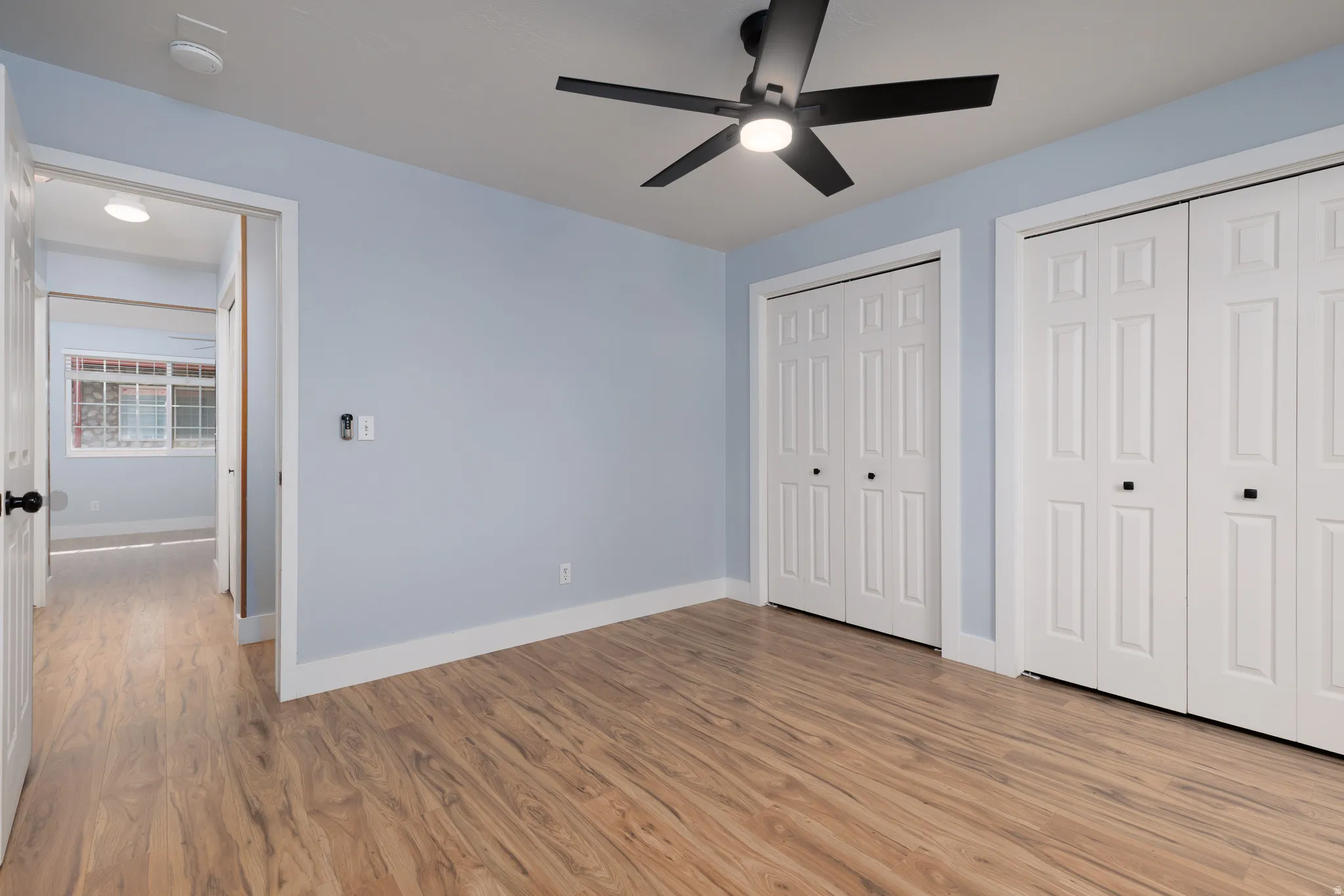 Room with wood-finish flooring, light blue walls, and white baseboards