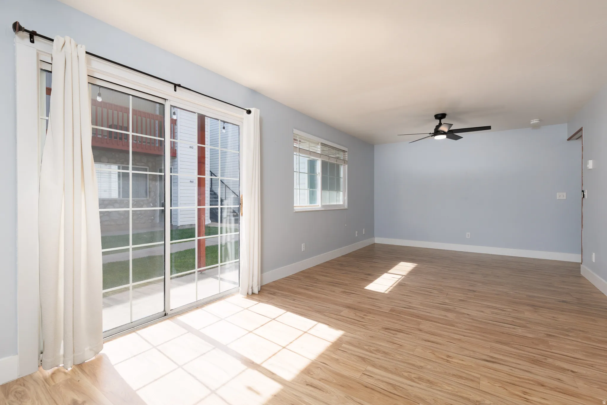 Spacious room featuring wood-finish flooring, light blue walls, and white baseboards
