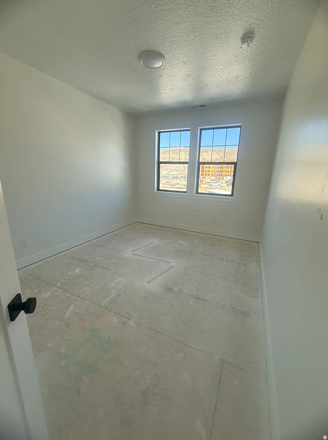 Bright room with dual pane windows, white painted walls, and ceiling-mounted light fixture