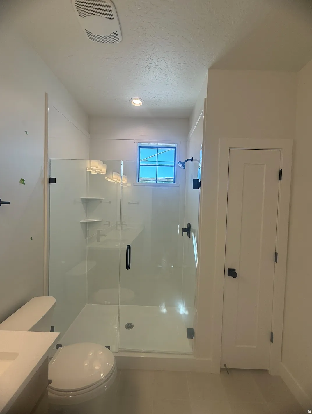 Modern bathroom featuring a glass-enclosed walk-in shower with a built-in bench, a window, and matte black fixtures