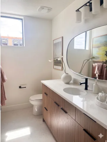 Contemporary bathroom featuring a wood-finish vanity with dark hardware, a white countertop with an integrated sink, and a matte black faucet
