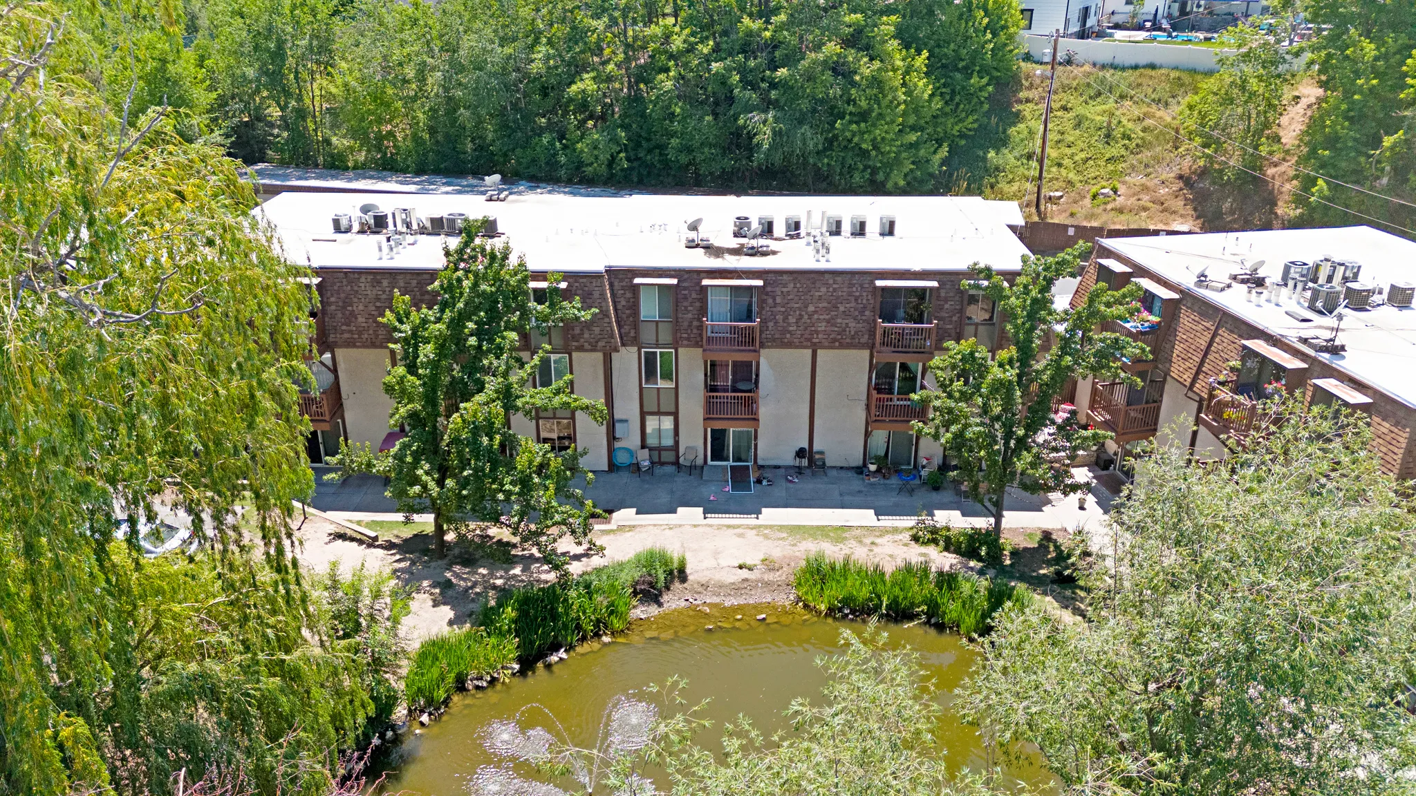 Three-story multi-unit building featuring individual balconies and patios