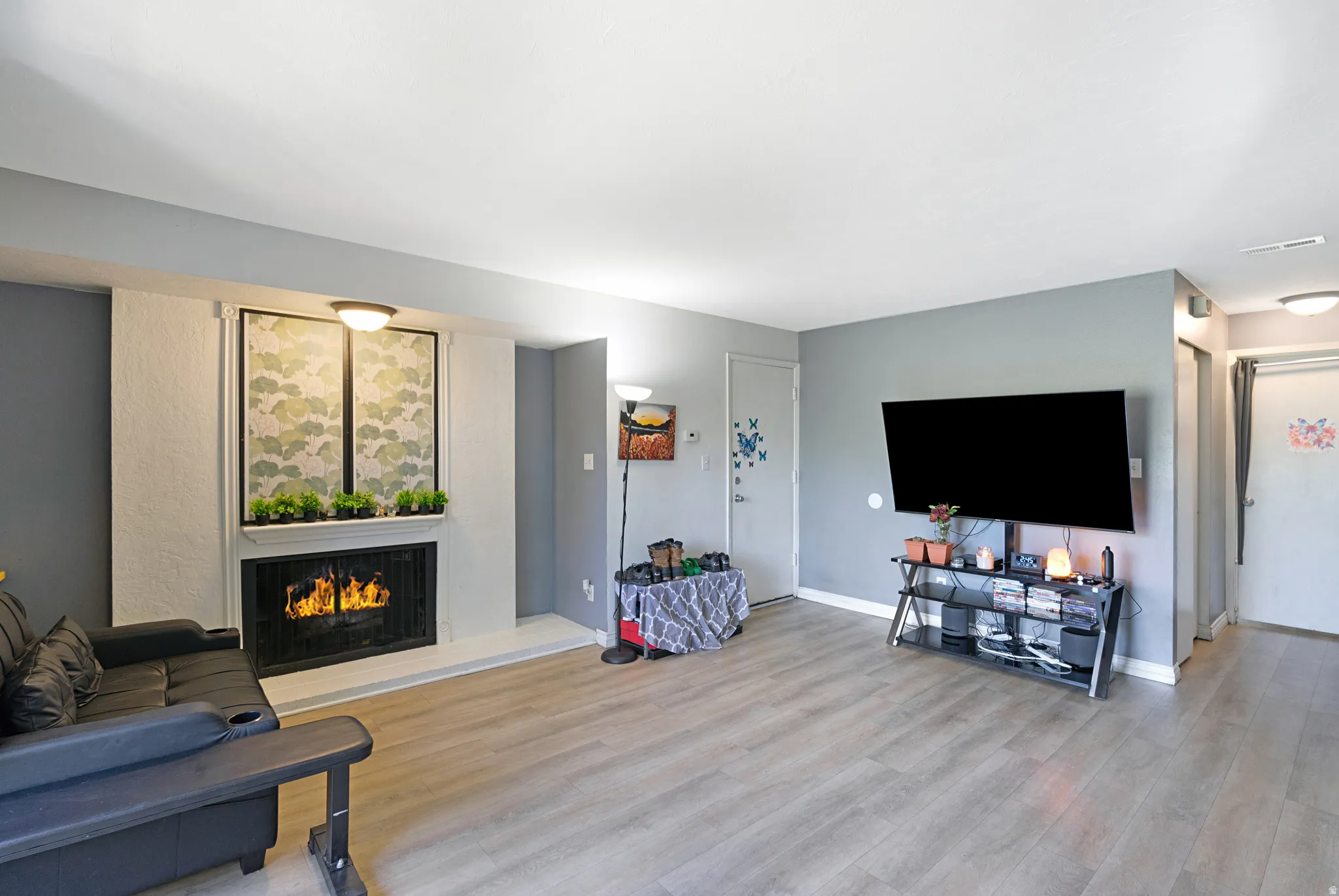 Living area featuring a fireplace with a white mantel, light wood-finish flooring, light gray wall paint, and recessed ceiling lighting