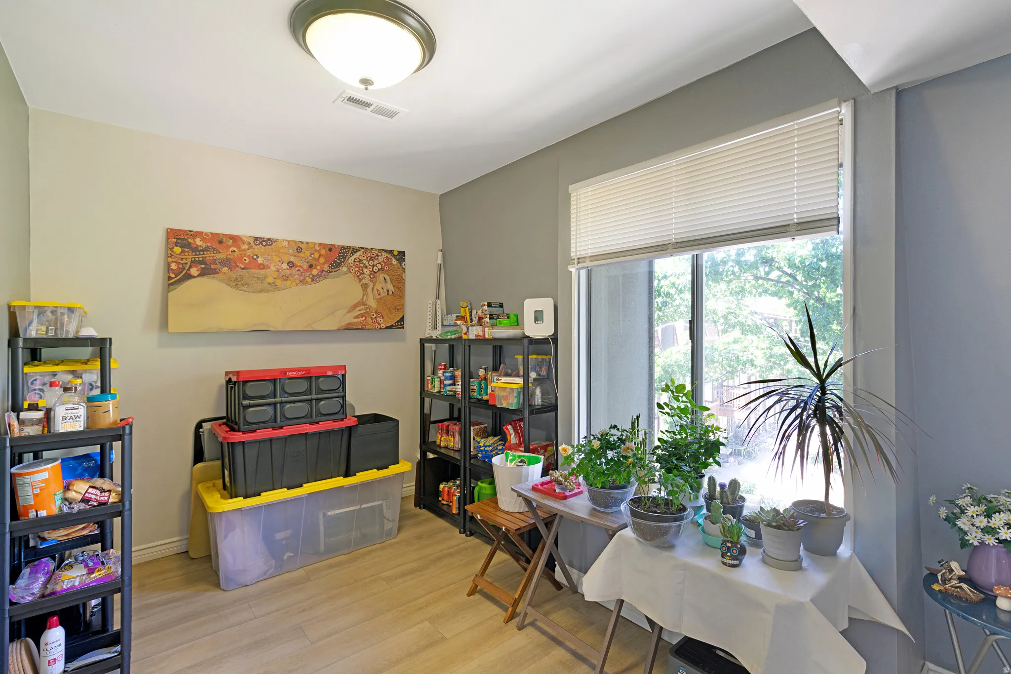 Spacious room with a large window, light-toned walls, and wood-finish flooring