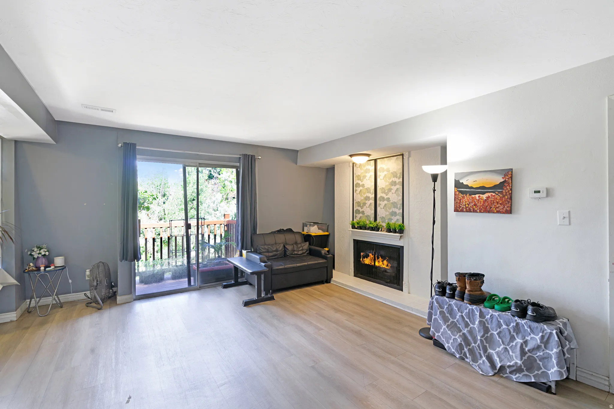 Open-concept living space with wood-finish flooring, a built-in fireplace, and sliding glass door access to an outdoor balcony