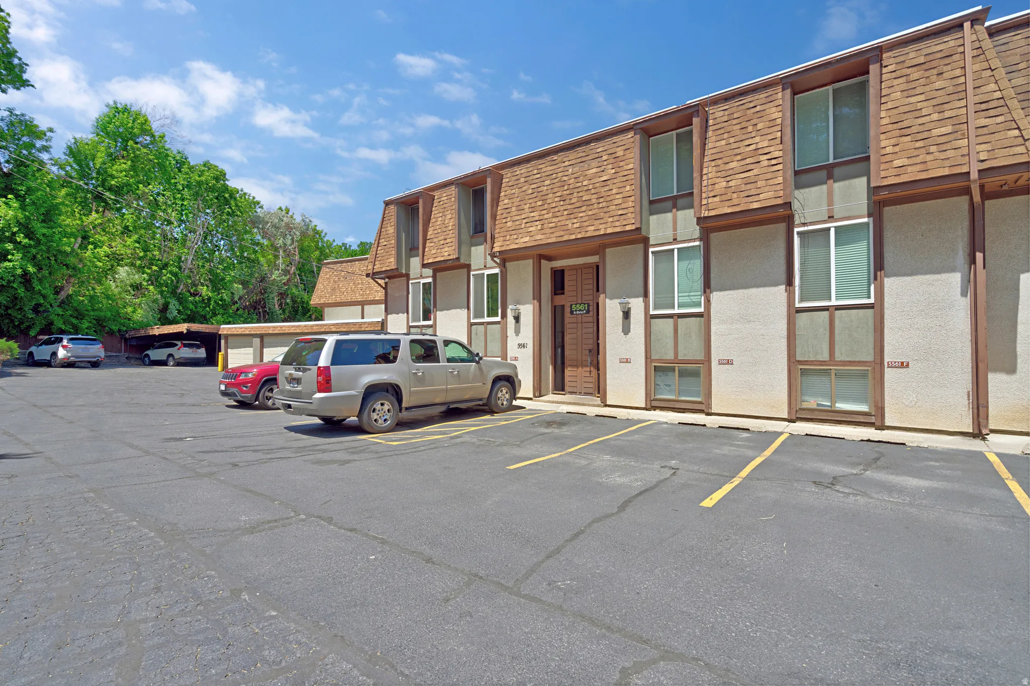 Multi-level townhouse-style units featuring textured exterior walls, brown trim accents, and pitched shingle roofs