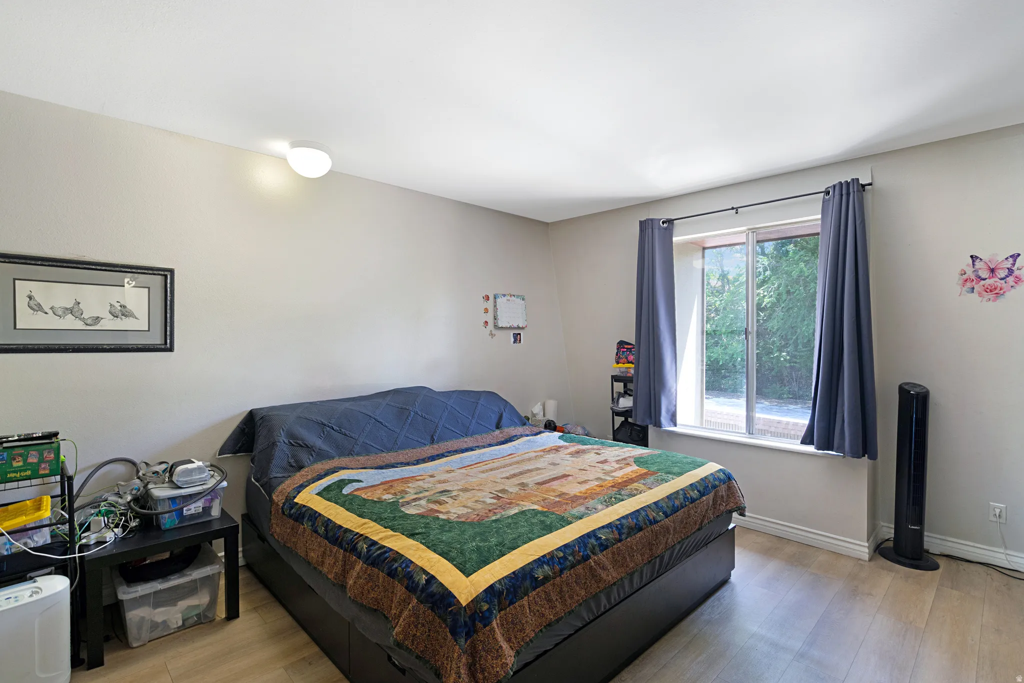 Neutral wall finishes, wood-finish flooring, and a window with a sill and blue drapes