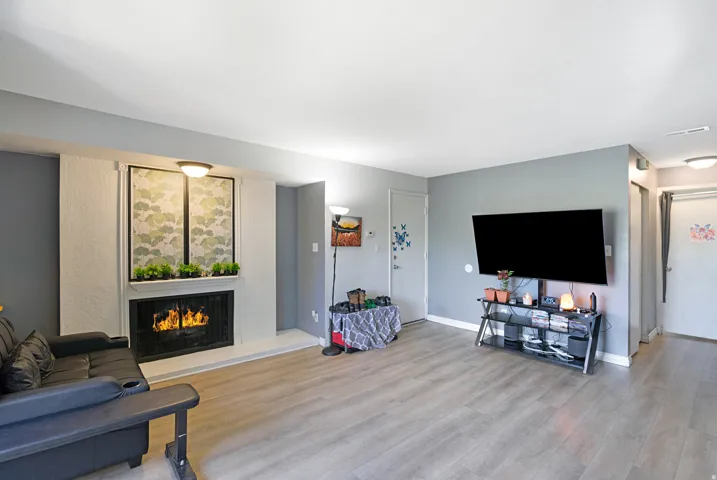 Living area featuring a fireplace with a white mantel, light wood-finish flooring, light gray wall paint, and recessed ceiling lighting