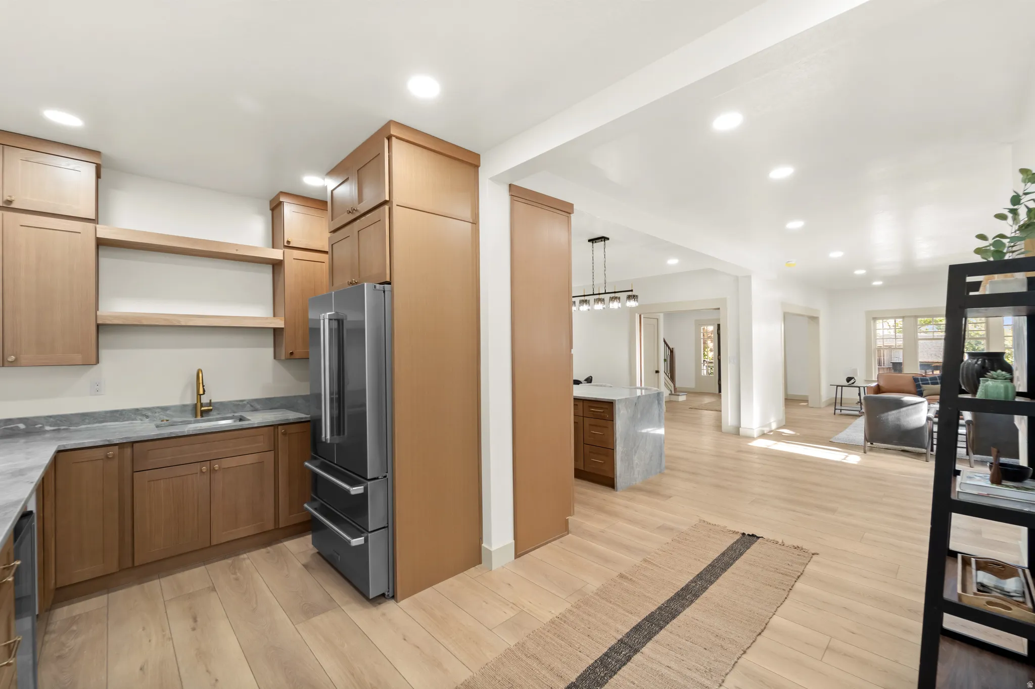 Kitchenette featuring wood-finish cabinetry, stone countertops, a stainless steel refrigerator, and gold-tone fixtures