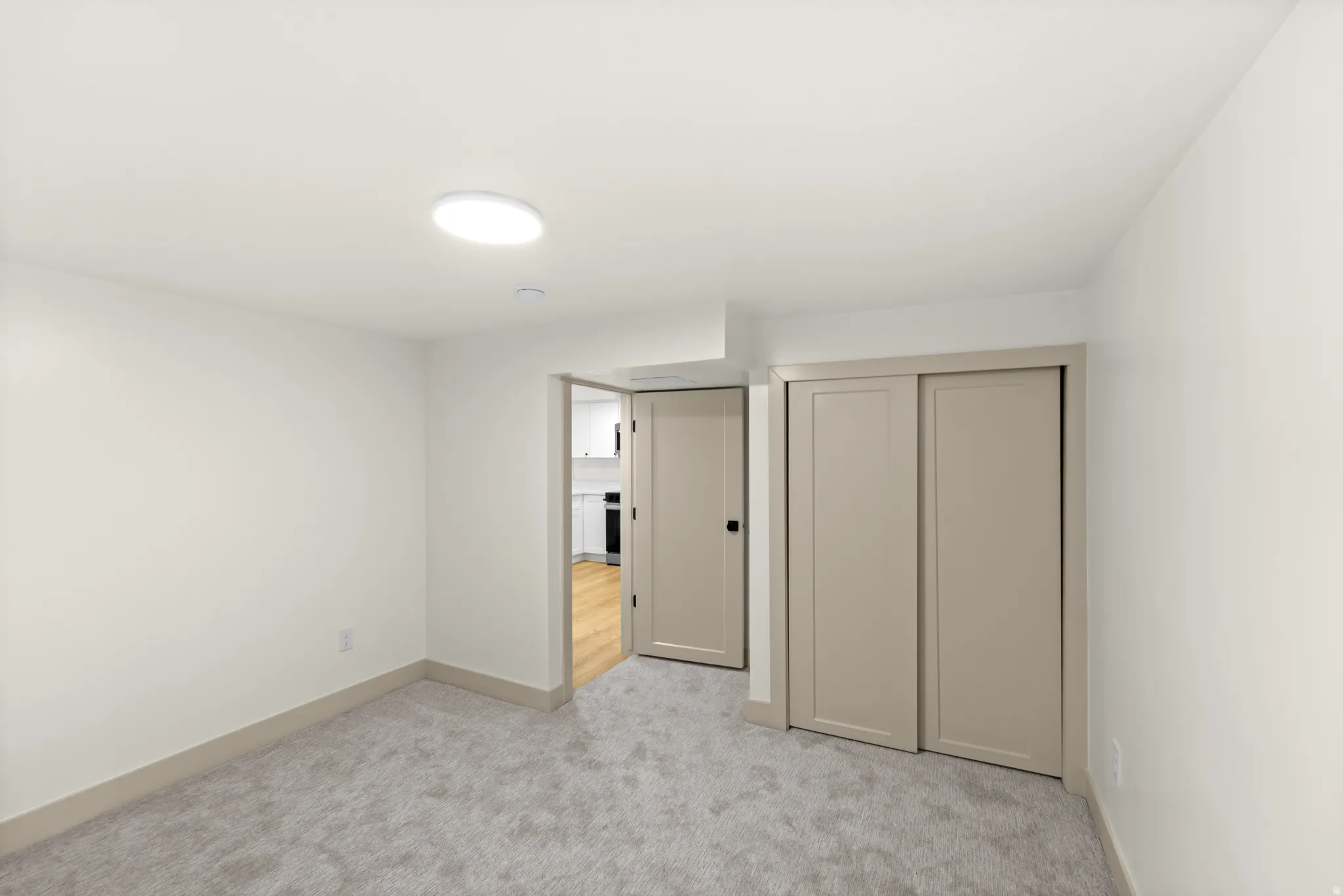 Neutral-toned room featuring a soft gray carpet, white walls, and a recessed ceiling light fixture