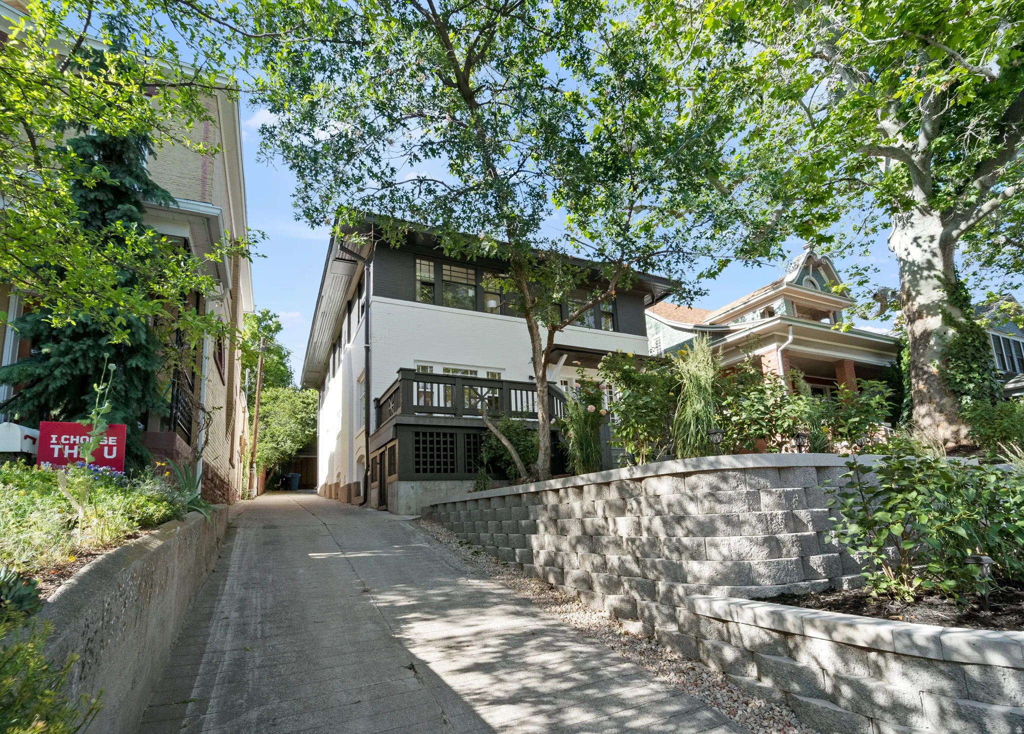 Modern exterior featuring a white facade with dark trim accents, a balcony with dark railings, and a concrete driveway