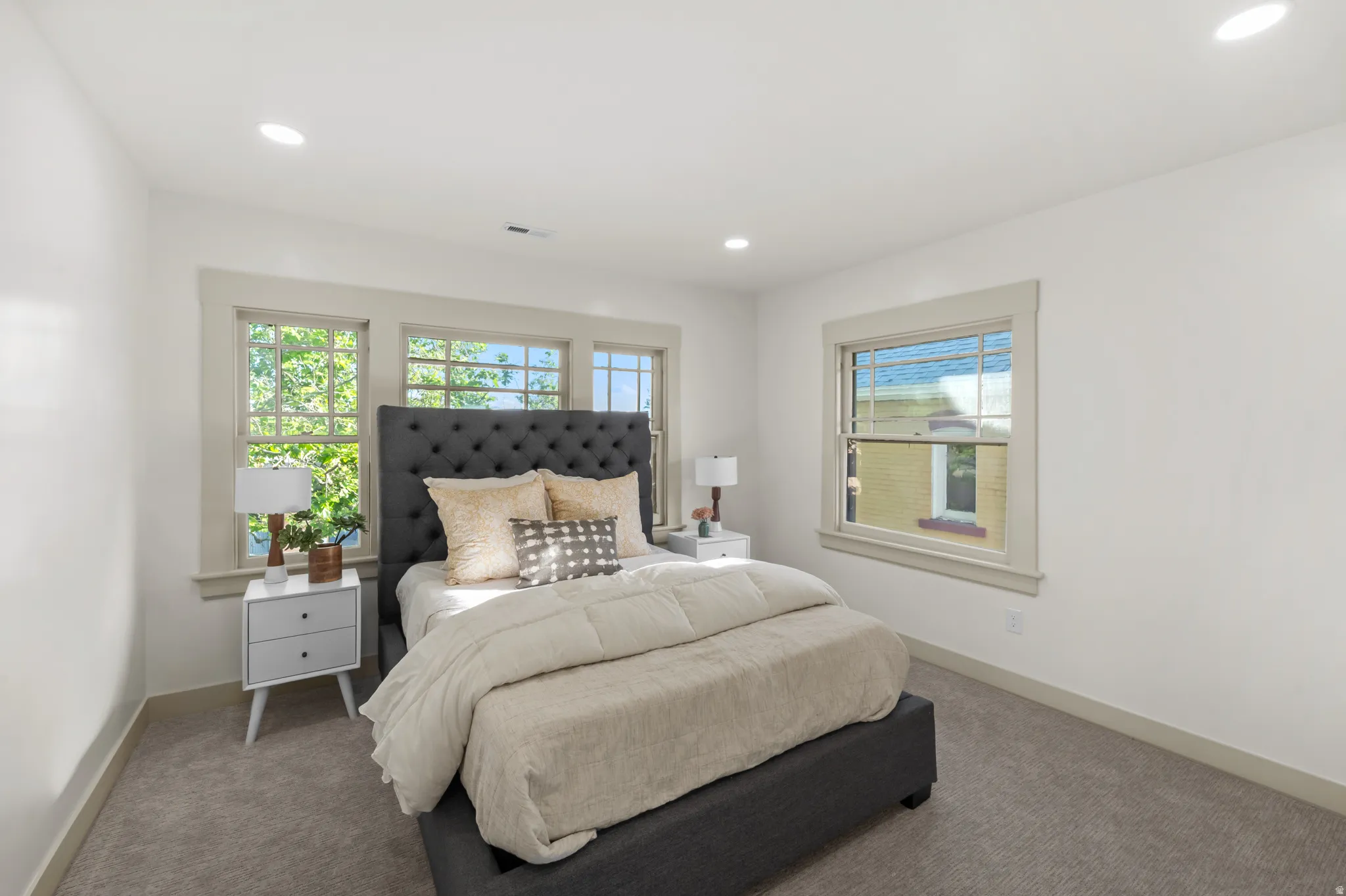 Bedroom featuring light gray carpeting, neutral wall paint, recessed lighting, and multiple windows with light-colored trim