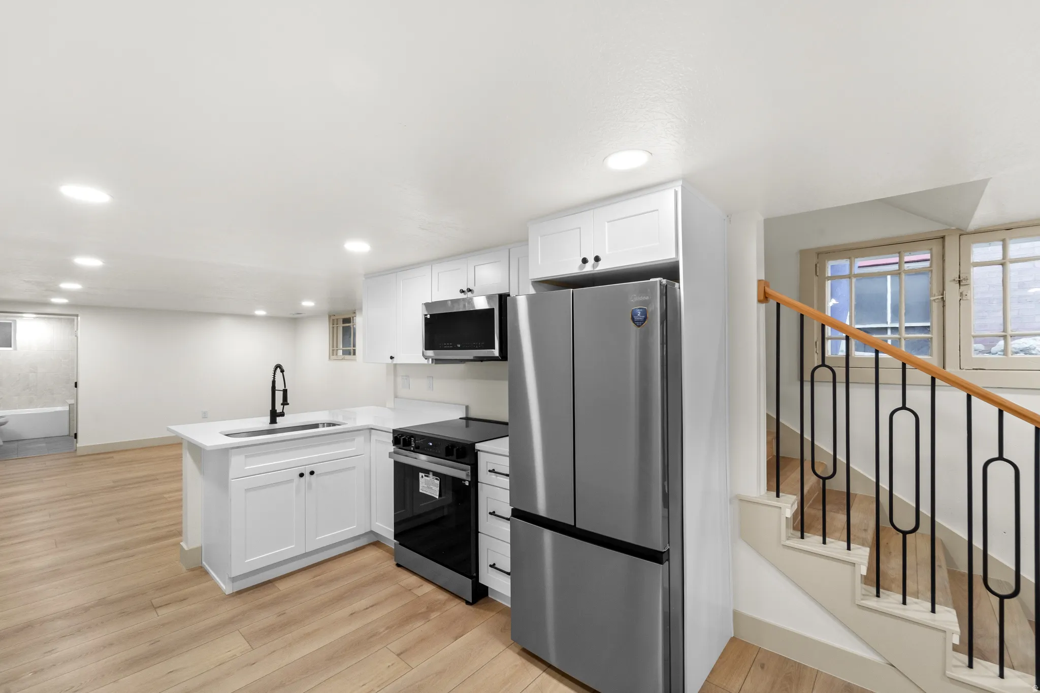 Modern kitchen featuring white cabinetry, a stainless steel refrigerator, an electric range, and an integrated microwave
