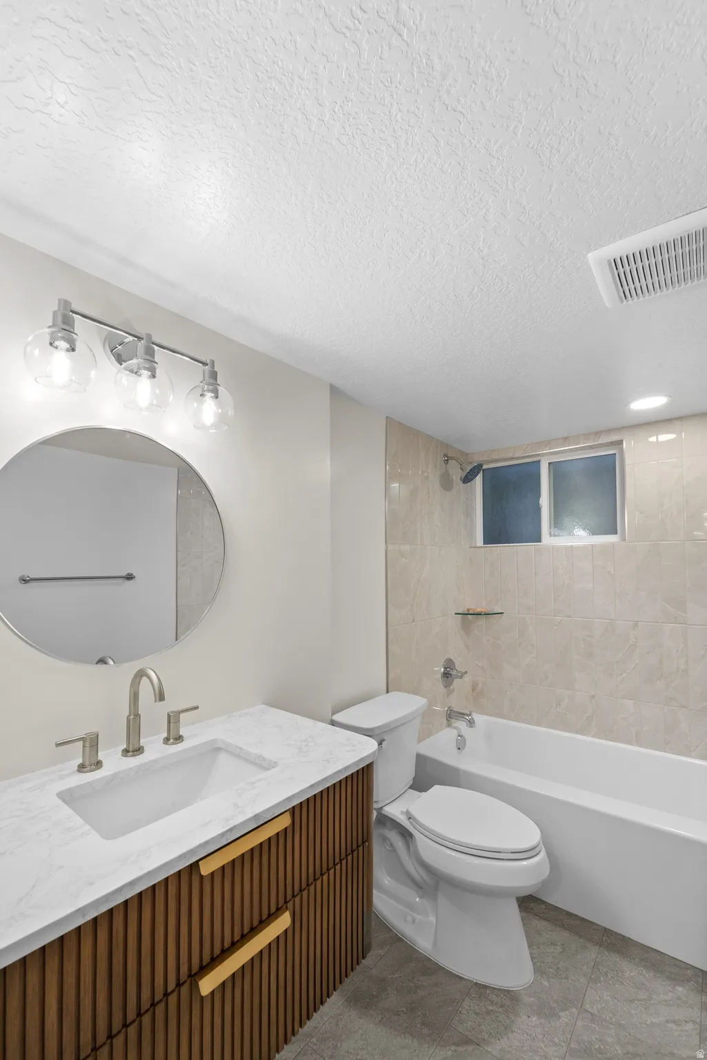 Bathroom featuring a contemporary wood-finish vanity with gold-tone hardware, a white rectangular undermount sink, and a light-toned countertop