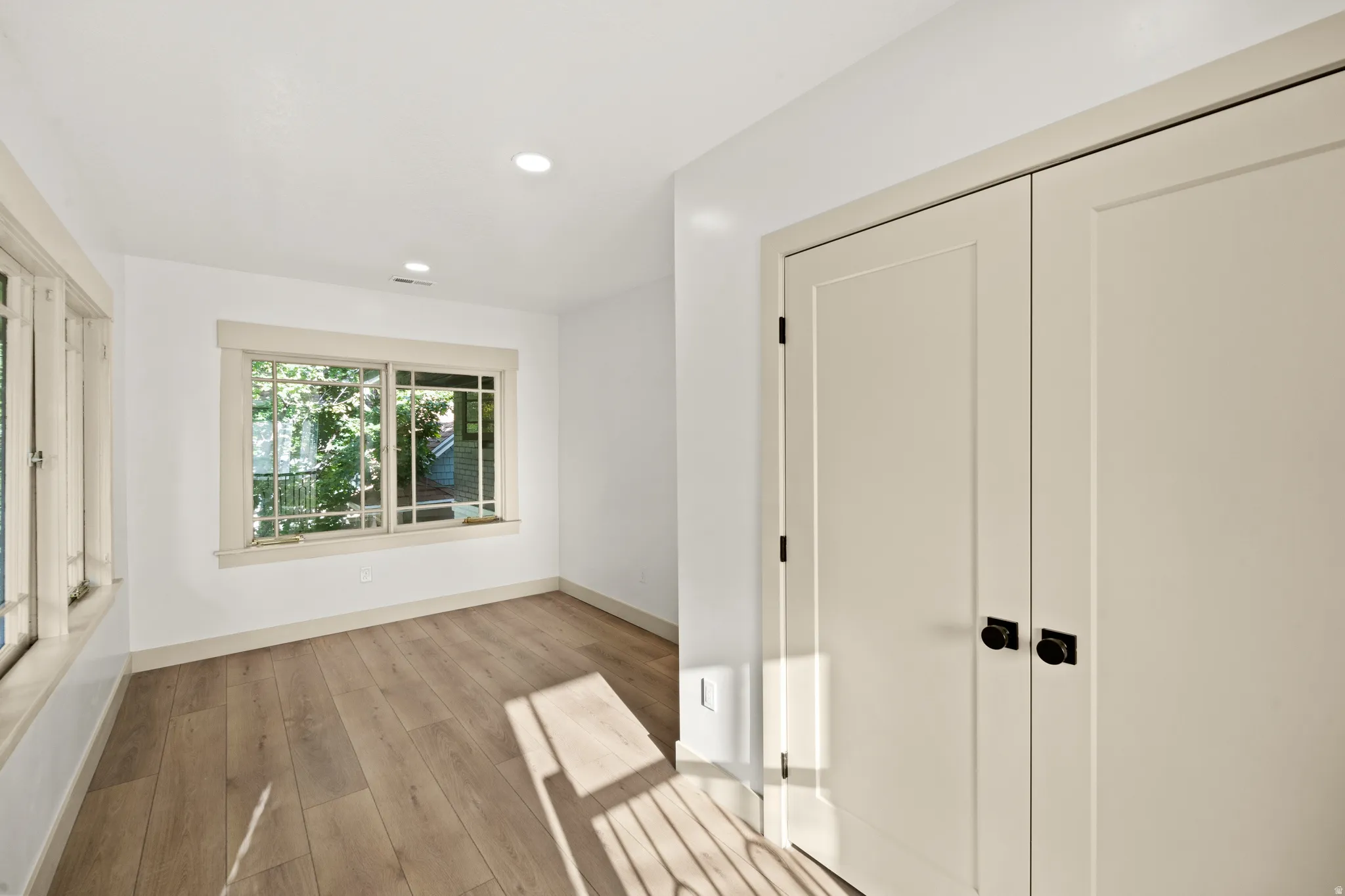 Room featuring wood-finish flooring, recessed lighting, and white walls
