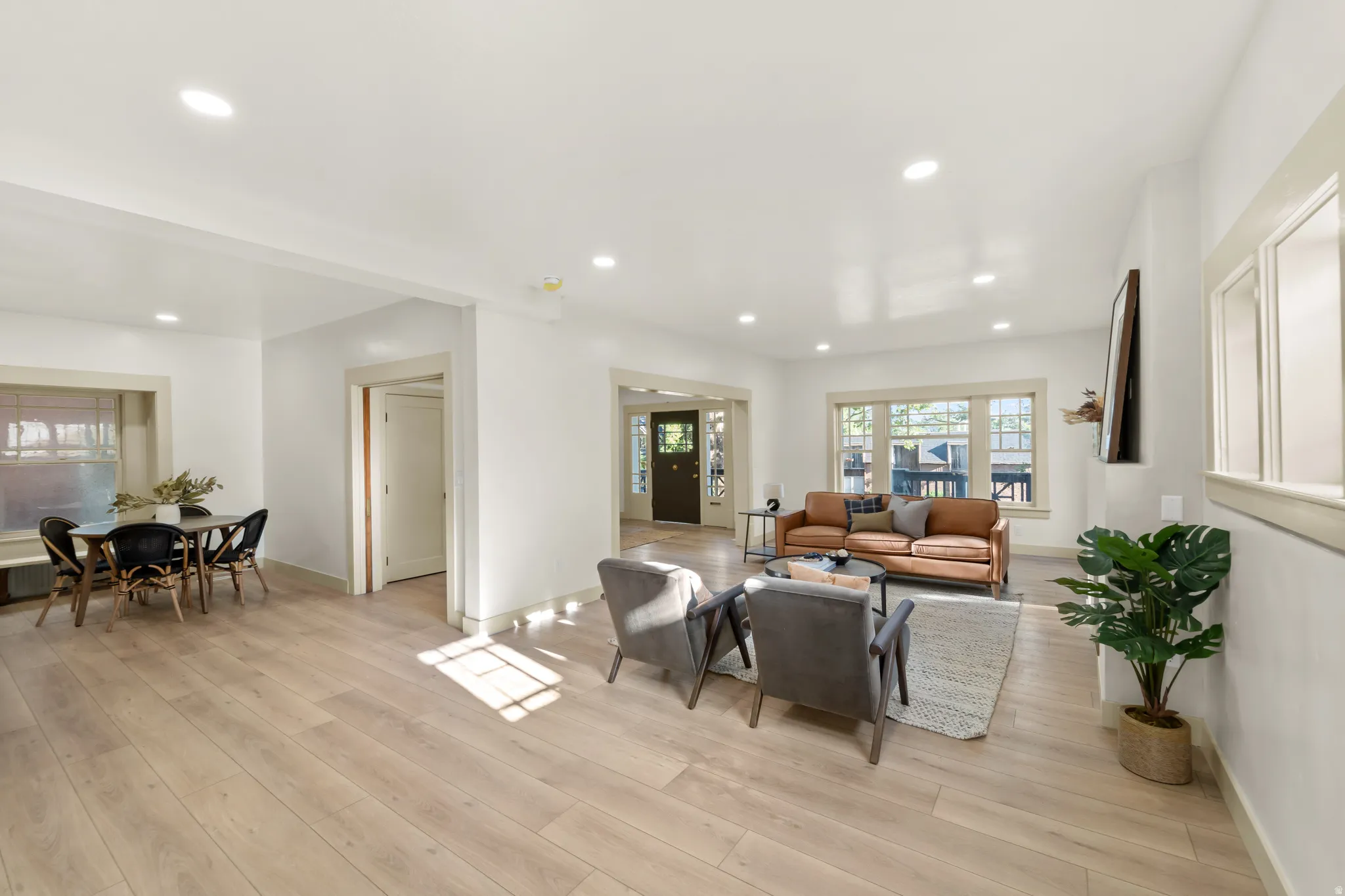 Bright living area featuring light wood-finish flooring, recessed lighting, and white walls with contrasting trim