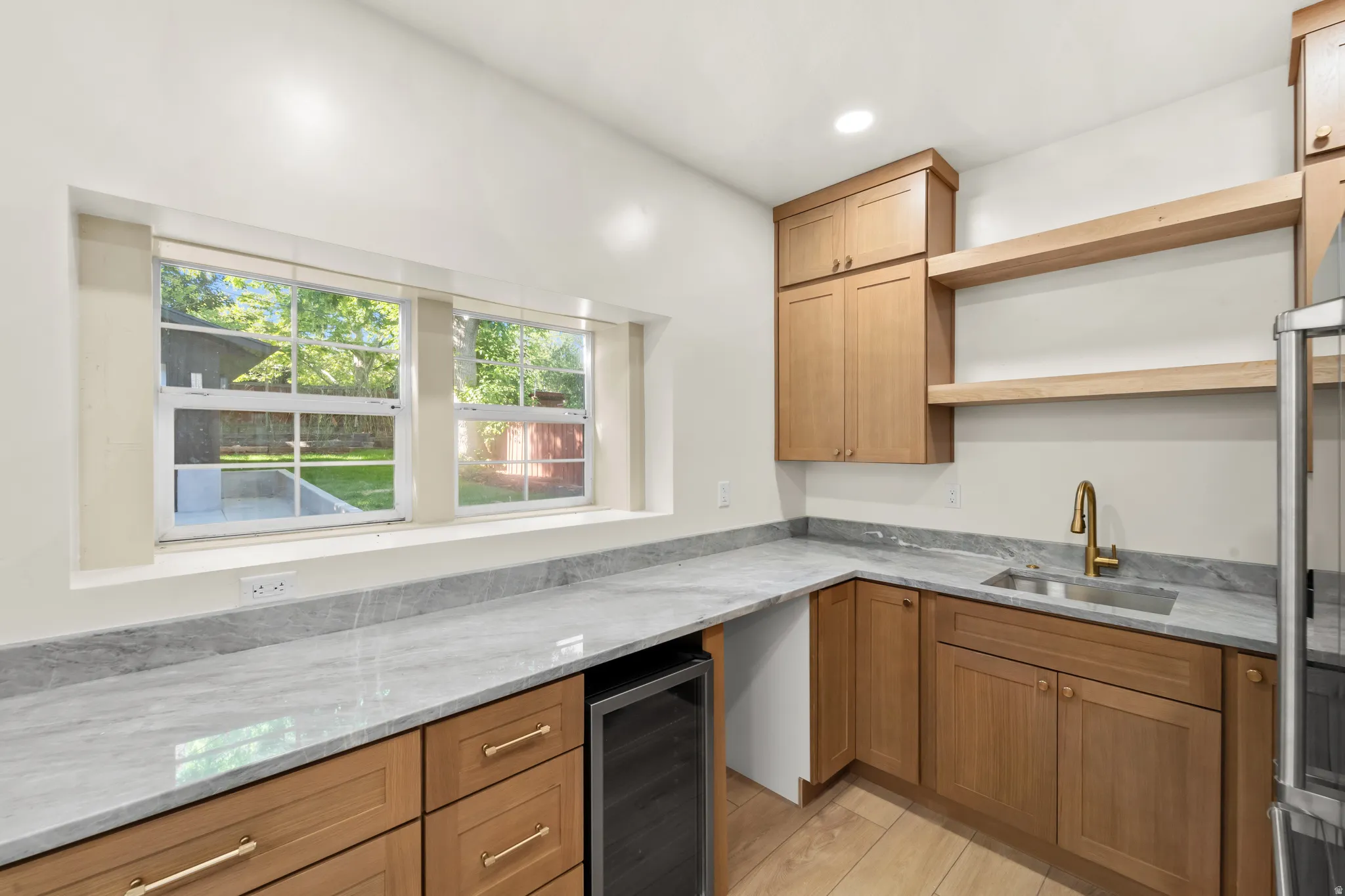 White walls complement light wood cabinetry, stone-finish countertops, and wood-finish flooring