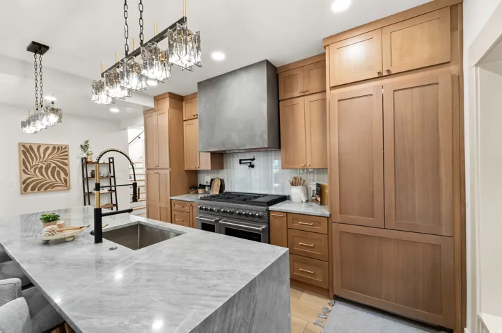 Spacious kitchen featuring an expansive island with a built-in sink and a contemporary black and brass faucet