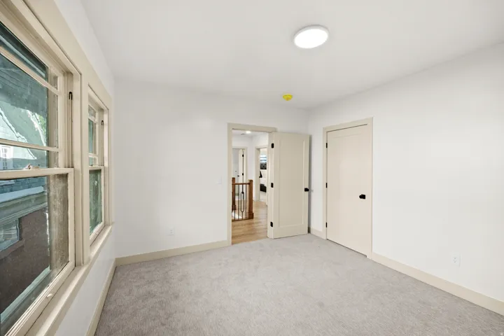 Room with light gray carpeting, neutral wall paint, and a double-hung window with wood trim